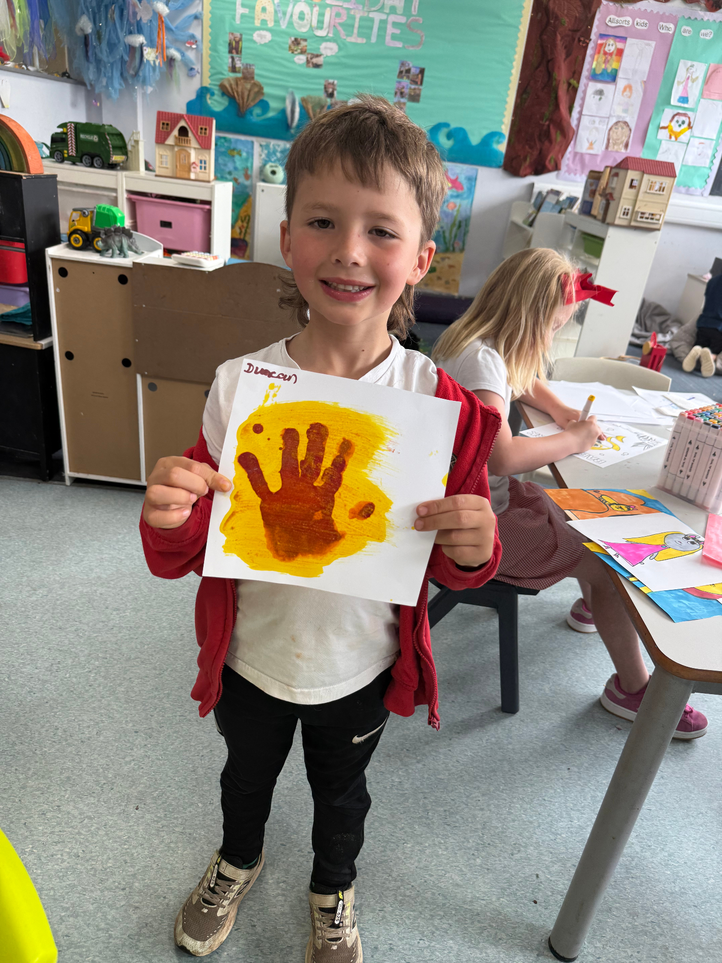 Child showing a painted handprint artwork at AllSorts