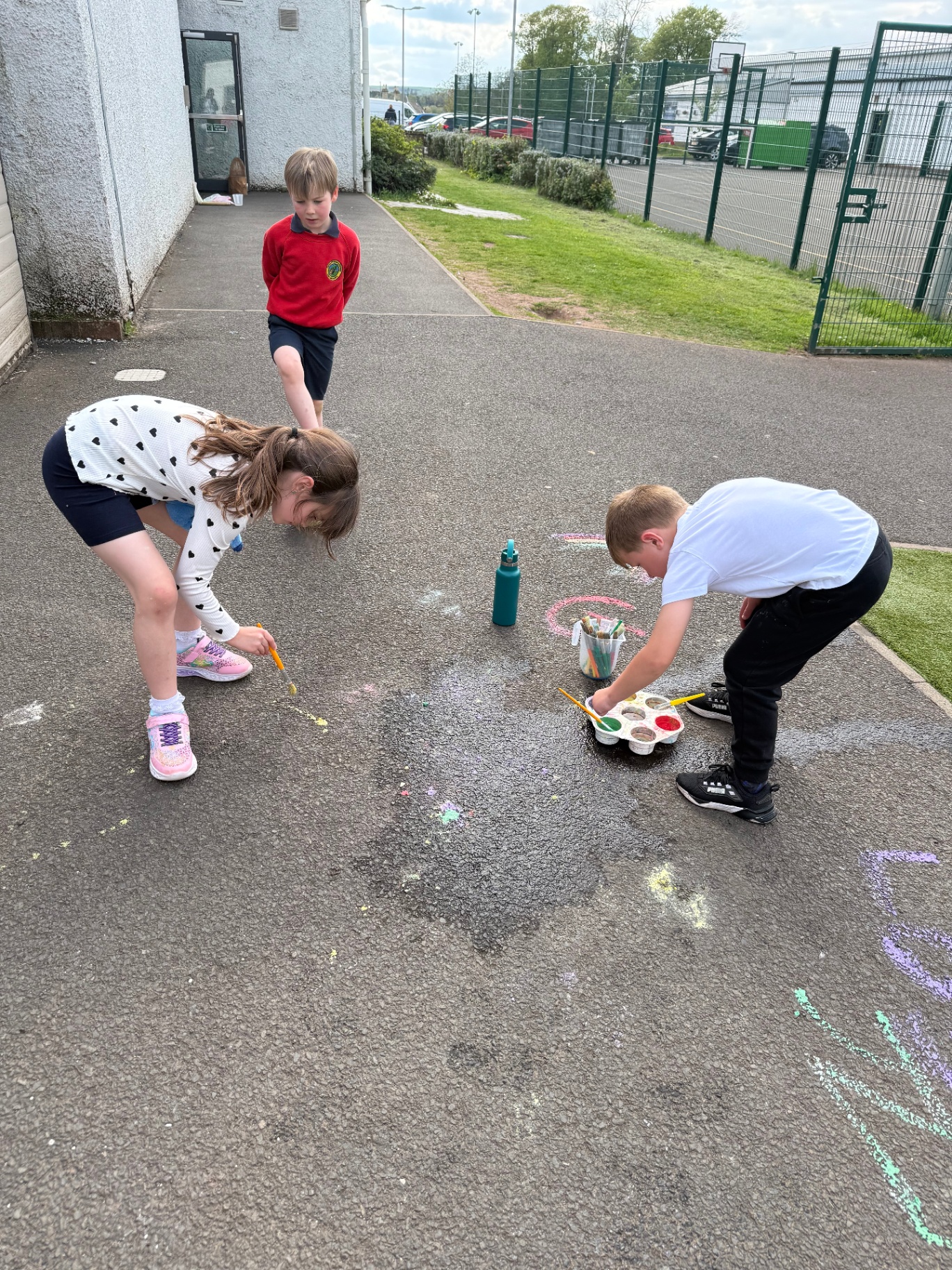 Children painting colourful chalk artwork outdoors at AllSorts
